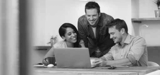 2 team members and a meneger leaning over a laptop